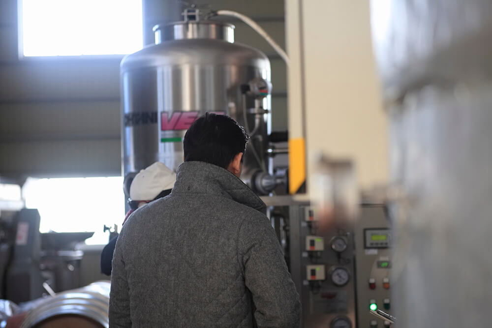 島崎さんの説明を受けながら、醸造設備を熱心に見る亀山さん。