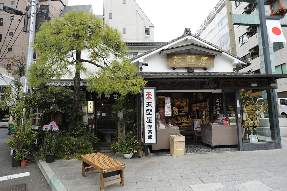店は神田明神の鳥居のすぐ横。右側はテイクアウト用の甘酒（350 円）や納豆、味噌、土産物のショップ、左側が甘味処になっている。