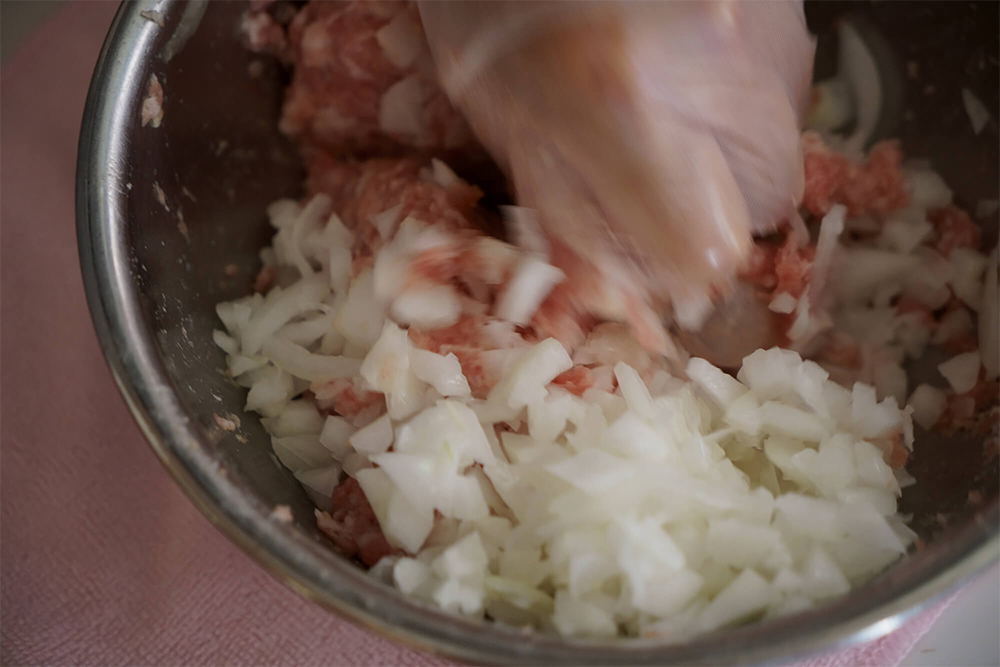 (D) 豚挽き肉、(C)、調味料を合わせ、約3分ギュッと握るように練る。粘りが出たら片栗粉をまぶしたタマネギを加え混ぜる。