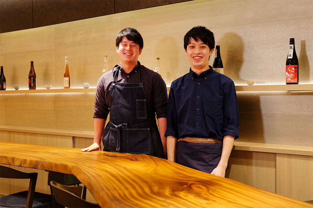 料理長の鈴木健也さん（左）は、ITベンチャーに３年勤めた後料理人を志し、2020年より島根県海士町の「島食の寺子屋」で１年間料理を学ぶ。2021年６月より「季苑」料理長に。唎酒師の土井貴文さん（右）は、大学在学中に日本酒に魅了され、2019年に唎酒師の資格を取得。翌年には山形県の桜川酒造で1カ月研修し、酒造りを学ぶ。2021年より現職。