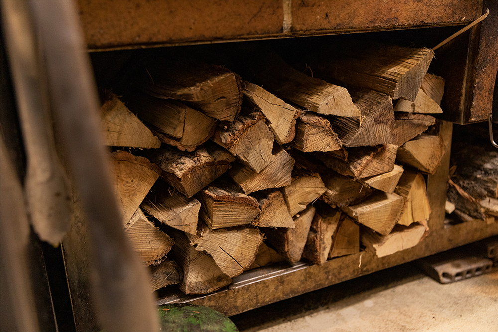 暖炉下に収められた薪。水分率や密度によって燃やし方を調整する。どんな熾火に仕立てるかは、毎回、肉質に合わせて調整している。