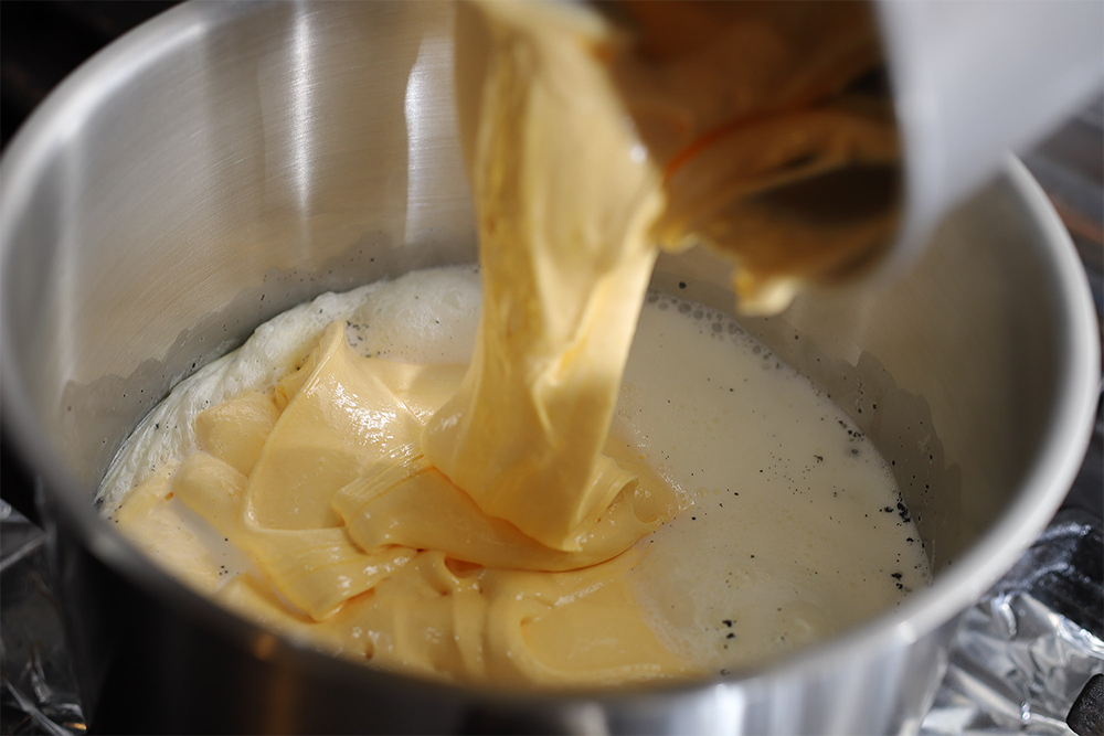【１】の牛乳が沸いたら（鍋のふちに泡が出る程度）、鍋の中心に【２】を流し入れる。周囲から牛乳の泡が上がってきたら、一気に混ぜる