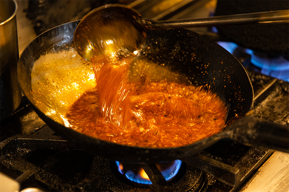 油を熱してスパイスの香りを出したところへ調味料を加える。高温になりすぎると香りが出ないため、油の温度のコントロールが肝だ。