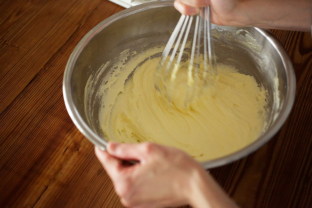 バター生地を作る。ボウルにバターを入れて、泡立て器でクリーム状にする。グラニュー糖を加え、ざらっとした感じがなくなってなじむまで、すり混ぜる。 [５]卵を加えて混ぜる
