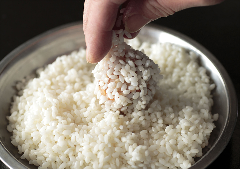 [３]もち米をまぶす 肉だねをゴルフボール程度の大きさに丸め、[１]のもち米をまぶす。