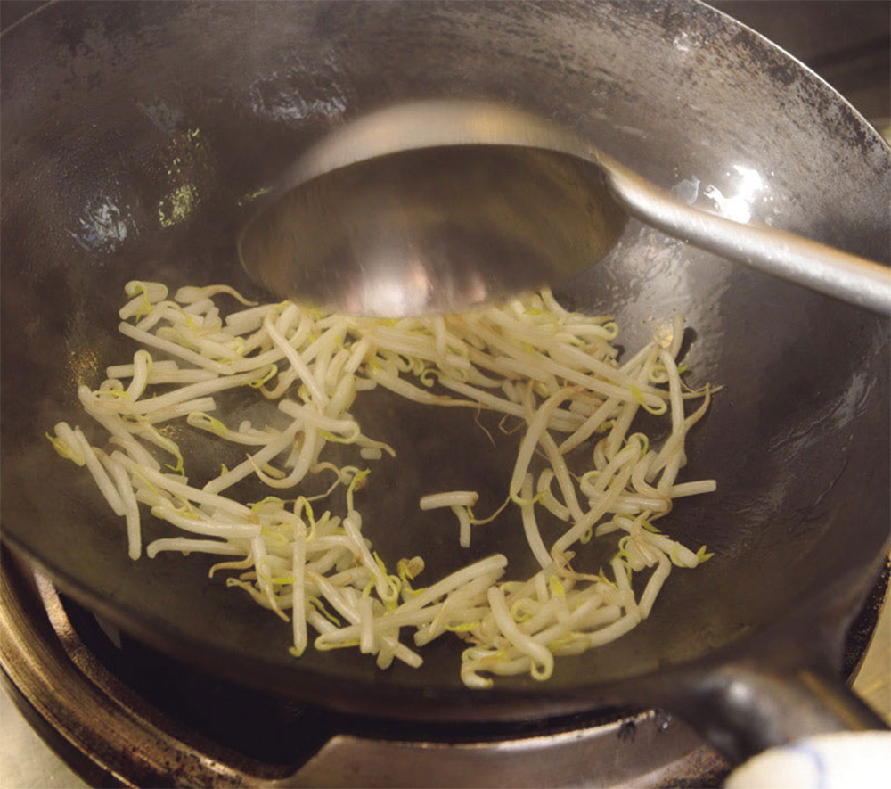 [６]モヤシを炒める 別の中華鍋にラードを小さじ1/2弱入れ、モヤシをひとつかみ加えて炒める。