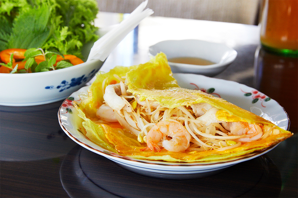 人気メニューのバインセオは、米粉の生地に具材を挟んだベトナム風お好み焼き。スガハラフォーではたっぷりのハーブと合わせて、ライスペーパーで巻いて食べる。