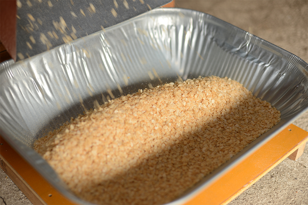 ５．押し機でひしゃぐ 米が熱いうちに押し機に入れ、ひしゃいで（平にして）いく。炒りすぎると米が壊れて粉になってしまうので、４～５はスピードが命。十分乾燥してから保存する。十分冷ましてから保存容器に入れる。