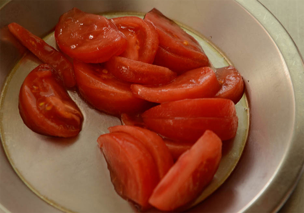 [１]トマトをくし形に切る トマトを８等分のくし形に切って皮をむき、さらに２等分のくし形に切る。