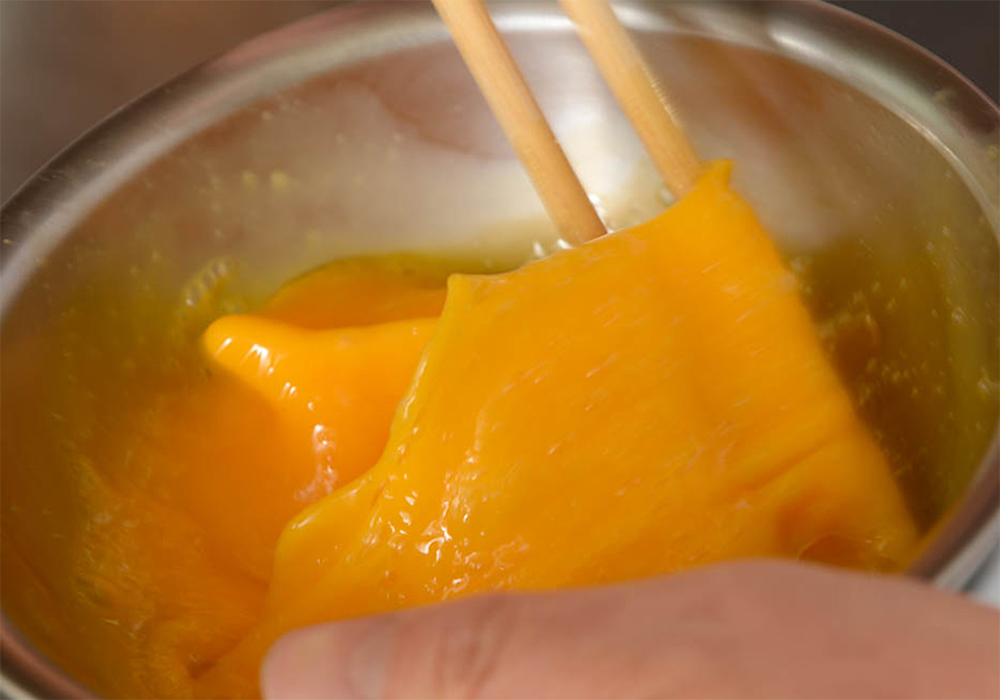 [２]卵をよく溶く 卵をボウルに割り入れ、塩、コショウを加える。菜箸でよく溶く。