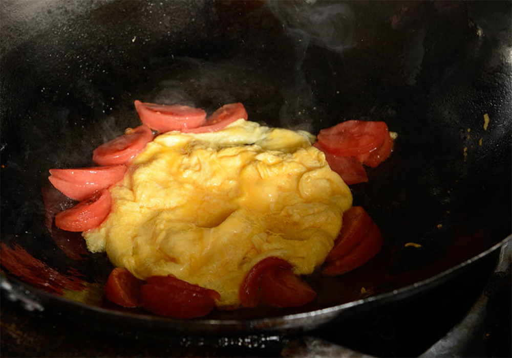 [６]トマトを加える 卵のまわりにトマトを置く。すぐに醤油をほんの少量たらす。