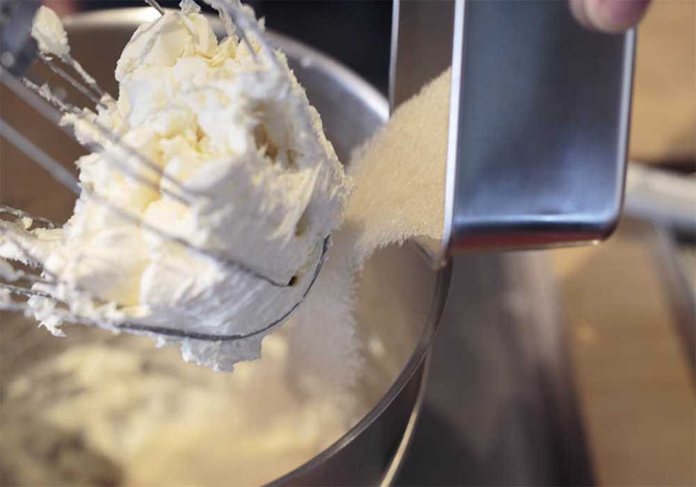 [１]クリームチーズをポマード状に ２㎝角程度にカットしたクリームチーズをミキサーボウルに入れ、中速のホイッパーでほぐす。きび砂糖を加え、ポマード状になるまで中速で混ぜる。