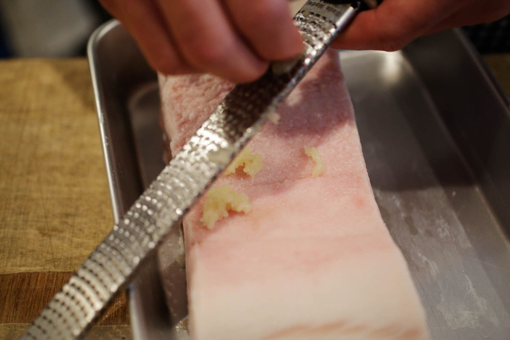 バットに肉を置き、ニンニクをすりおろす。