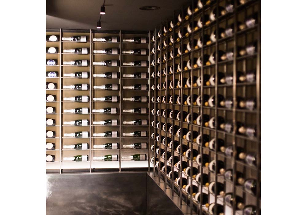 （写真）個室に通じる１階壁面のワインボトルは圧巻のディスプレー。同店ではほとんどの客がワインをオーダーするという。地階のワインセラーには500銘柄を揃え、ワインメーカーとコラボしてテイスティング会も開いている。