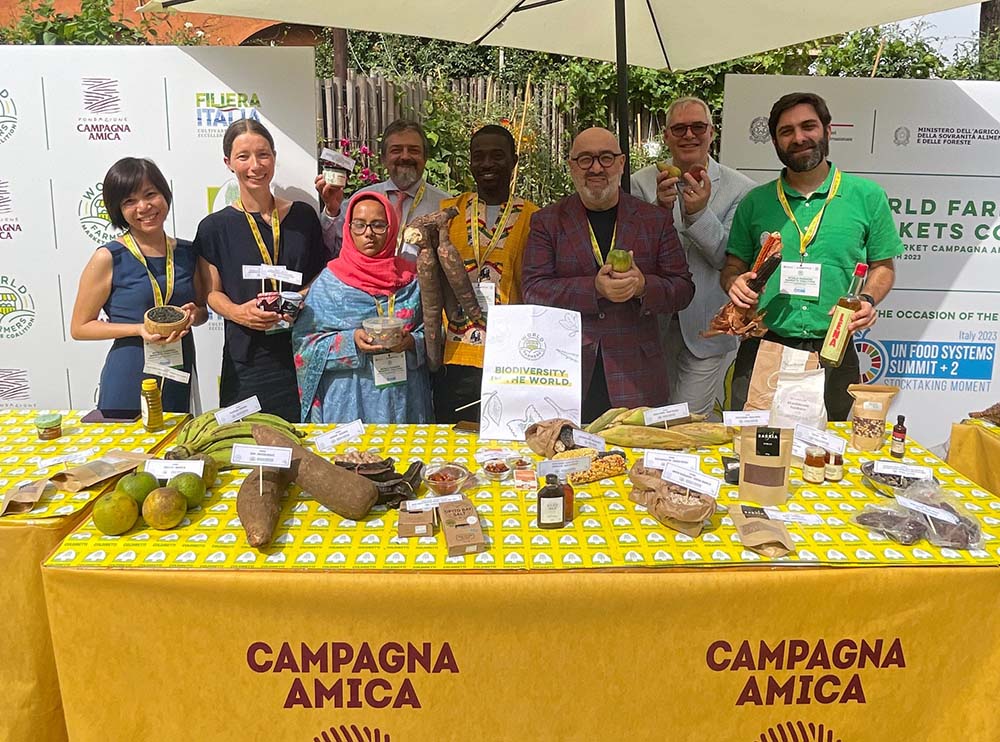 （写真）2023年７月、国連がローマで開催した「食料システムサミット＋2 ストックテーキング・モーメント」で、WFMCは活動内容を発表。会場となったローマのチルコ・マッシモ地区「カンパーニャ・アミーカ・マーケット」にて、WFMC事務局長カルロ・トロッコリ氏（右から3番目）と各国の代表たち。