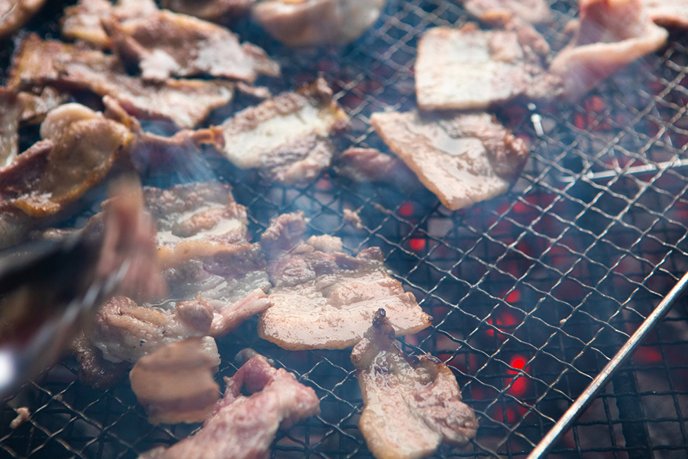 BBQグリルの周りには食欲を刺激する音と香りが立ち込めていた。炭火で焼いた豚肉は、塩だけで抜群においしい。